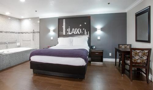 a bedroom with a bed and a bathtub and a bed and a bathroom at Elev8 Hotel Los Angeles, LAX in Inglewood