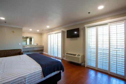 a bedroom with a bed and a television and windows at Elev8 Hotel Los Angeles, LAX in Inglewood