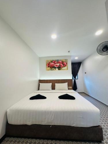 a bedroom with a large white bed with black pillows at Ar Rayyan Hotel in Tanah Rata