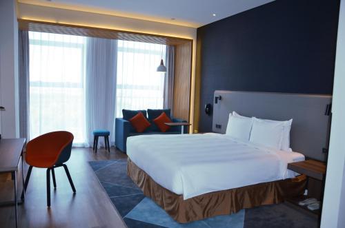 a hotel room with a large bed and a chair at Holiday Inn Express Harbin Qunli by IHG in Harbin