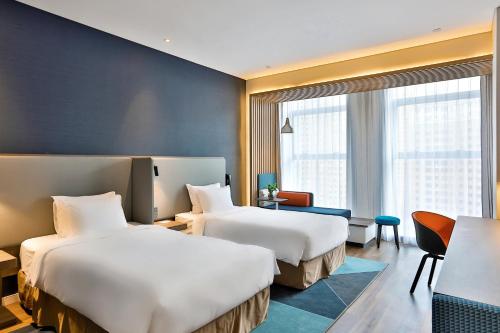 a hotel room with two beds and a desk at Holiday Inn Express Harbin Qunli by IHG in Harbin
