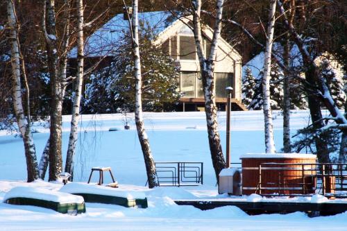 a park covered in snow with trees and a house at Vezezeris in Gaugariai