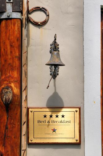 a bell on the side of a wall with a sign at TNiqua Stable Inn in Plettenberg Bay