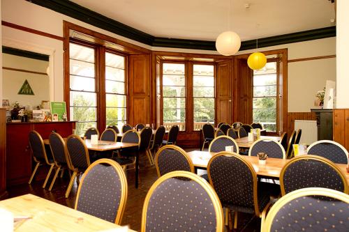 a dining room with tables and chairs and windows at YHA Langdale in Ambleside