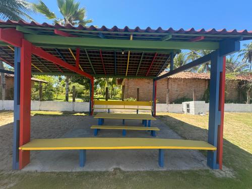 a picnic shelter with three benches in a park at Casa com jacuzzi piscina e comodidade a beira mar in Maragogi