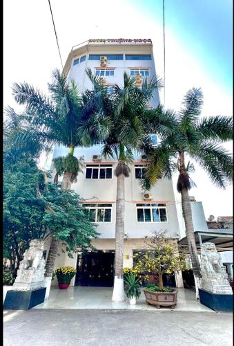 a building with palm trees in front of it at Trường Ngọc Hotel in Buon Ma Thuot