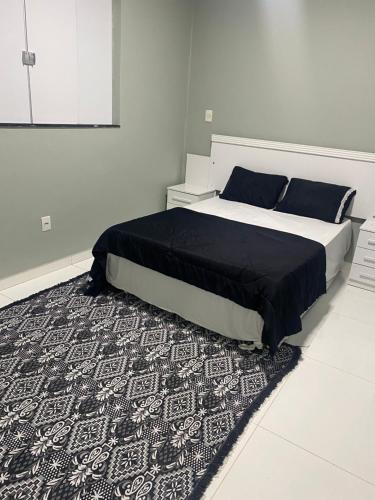 a bedroom with a bed with a black and white rug at Casa luxo ferias in Porto Seguro