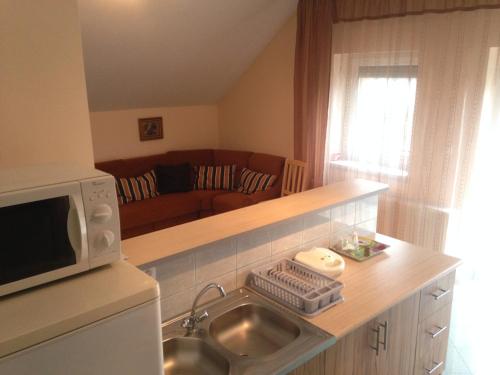 a kitchen with a sink and a microwave at Szemán Kis Apartmanok in Harkány