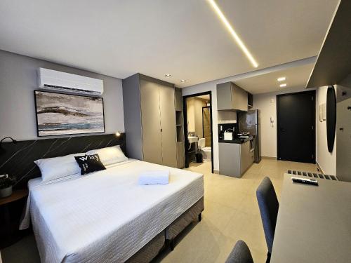 a bedroom with a large white bed and a kitchen at Lindo Studio no Coração de Tambaú in João Pessoa