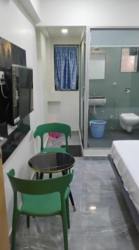 a room with two green chairs and a bathroom at Hotel Sai Nidhi Residency in Thane