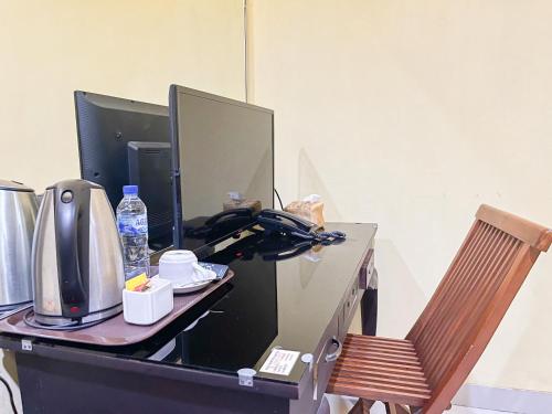 a desk with a computer monitor and a chair at Kartika Hotel Syariah Pacitan Mitra RedDoorz in Pacitan