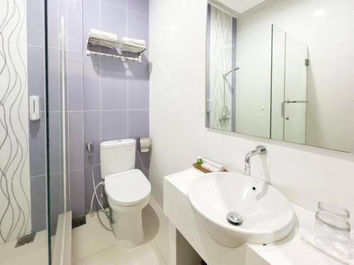 a white bathroom with a toilet and a sink at Kartika Hotel Syariah Pacitan Mitra RedDoorz in Pacitan