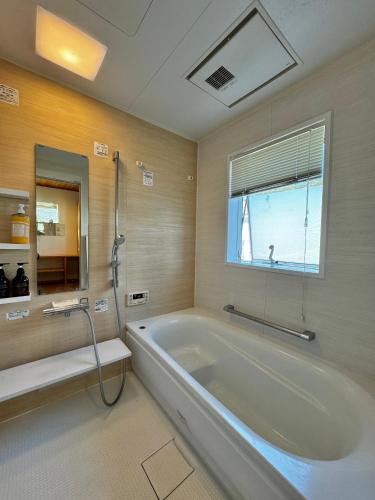 a large bathroom with a tub and a window at Kamiya Cottage in Hayama