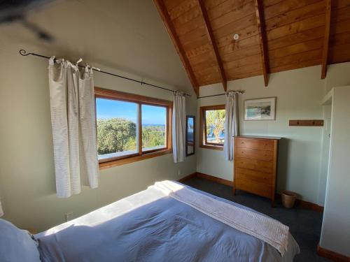 a bedroom with a large bed and a window at Above the Bay in Hahei
