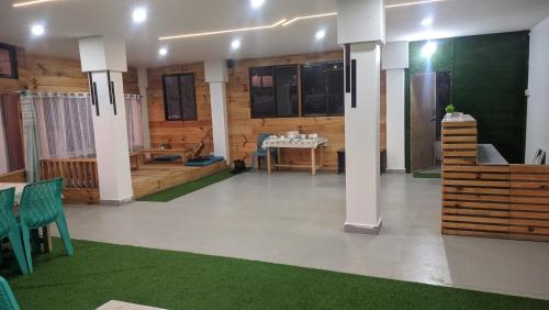 a living room with a table and a room with green carpet at Hotel Horizon, Ziro in Ziro