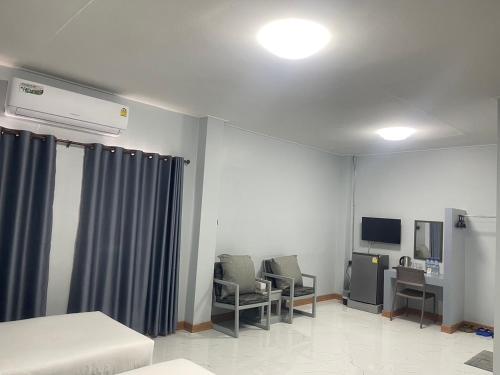 a room with two chairs and a table and a tv at Chainatgrand Hotel in Ban Khung Mae Luk On