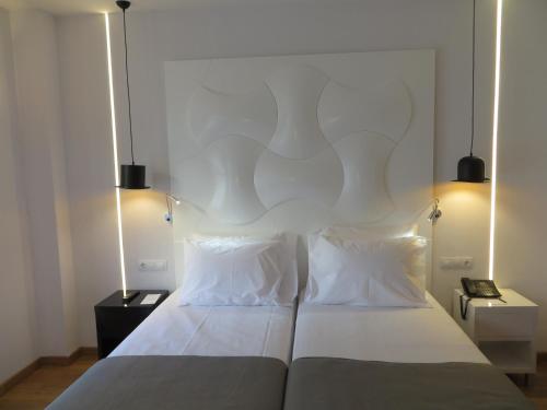 a bedroom with a large white bed with two pillows at Evenia Rocafort in Barcelona