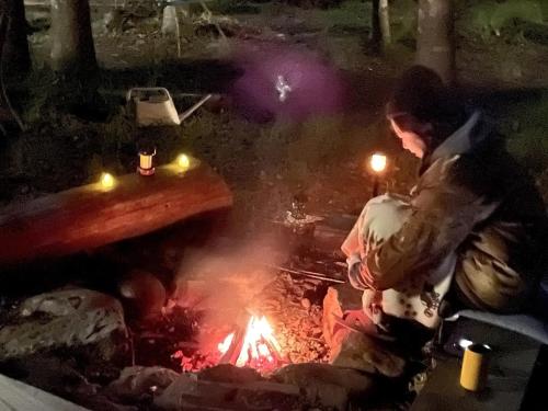 a man is cooking over a campfire at night at Starry Forest Inn KURIHAI in Oita