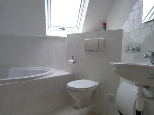 La salle de bains blanche est pourvue de toilettes et d'un lavabo. dans l'établissement House of Rootz, à Frankenau
