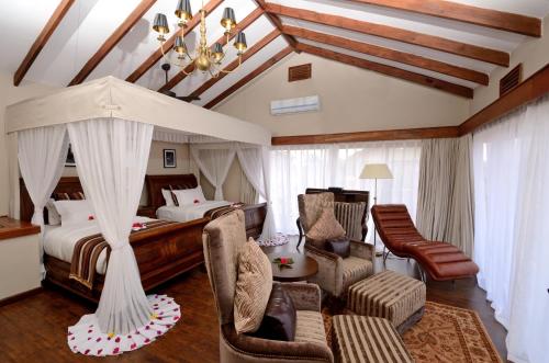een slaapkamer met een bed, een bank en een stoel bij Ngorongoro Oldeani Mountain Lodge in Oldeani