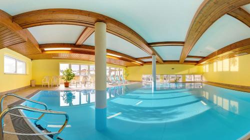 a large indoor swimming pool with blue water at Hotel-Pension Egger in Grossarl