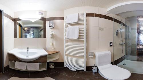 a bathroom with a sink and a shower and a toilet at Hotel-Pension Egger in Grossarl