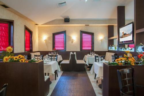 a restaurant with white tables and chairs and flowers at Hotel Domaine Peshtera in Peshtera
