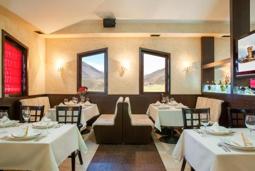 a restaurant with white tables and chairs and windows at Hotel Domaine Peshtera in Peshtera