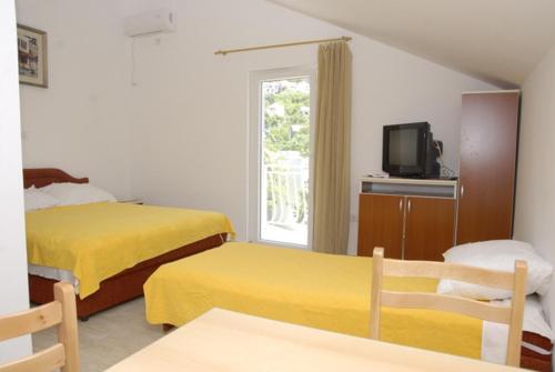 una camera d'albergo con due letti e una televisione di Apartments Dosljak a Tivat