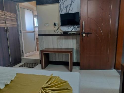 a room with a door and a table and a television at Hotel Nagaon Point in Nowgong
