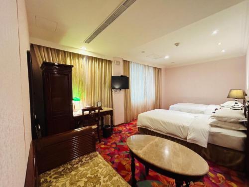a hotel room with two beds and a table at Royal Seasons Hotel Taipei ‧ Nanjing W. in Taipei