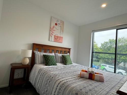 a bedroom with a bed with green pillows and a window at A Hidden Gem near Hagley park in central city in Christchurch