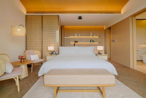 a bedroom with a large white bed and two chairs at Chengdu Expo Waterfall Hotel - MGallery Collection in Chengdu