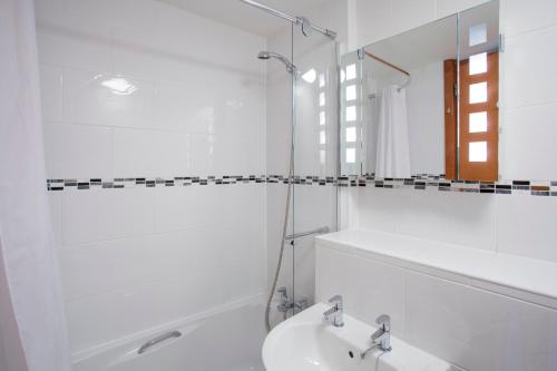 a white bathroom with a sink and a mirror at Robinson College - University of Cambridge in Cambridge