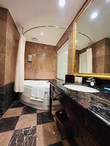 a bathroom with a tub and a sink and a mirror at Royal Seasons Hotel Taipei ‧ Nanjing W. in Taipei