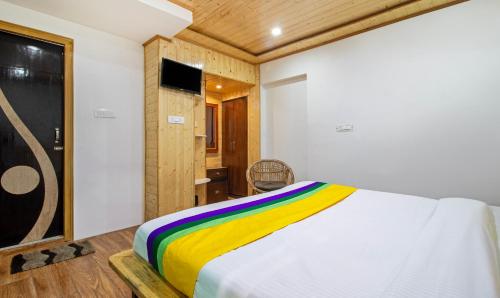 a bedroom with a bed with a colorful blanket at Itsy Hotels Shri Gv Inn, 600 Mtrs From Tiffin Top in Nainital