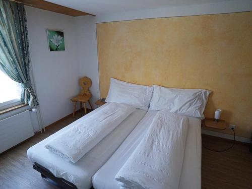 a bedroom with a large bed with white sheets and a window at Sternen Doppelzimmer in Benken