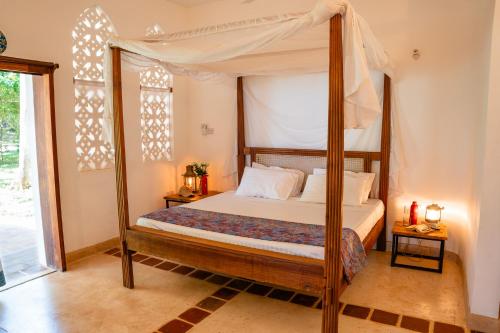 a bedroom with a canopy bed and a window at Mawimbi Cottage in Ukunda