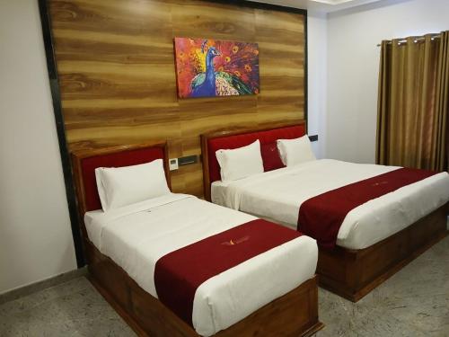 a hotel room with two beds and a painting on the wall at Ramraj Resort in Kanyakumari
