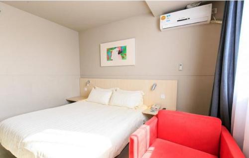 Habitación pequeña con cama y silla roja. en Jinjiang Inn Beihai Beibu Gulf Square, en Beihai