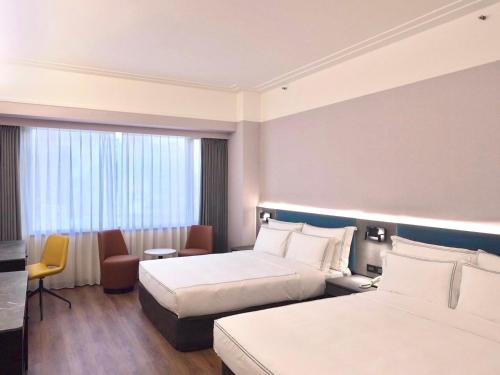 a hotel room with two beds and a window at Fullon Poshtel Jhongli in Zhongli