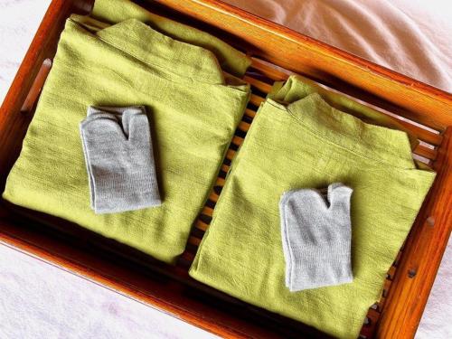 a wooden tray with green napkins and socks on a bed at Yukemuri no sato azumaya in Beppu