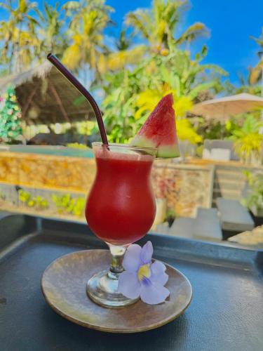 a drink with a slice of watermelon and a flower on a table at The Jini House in Ahangama