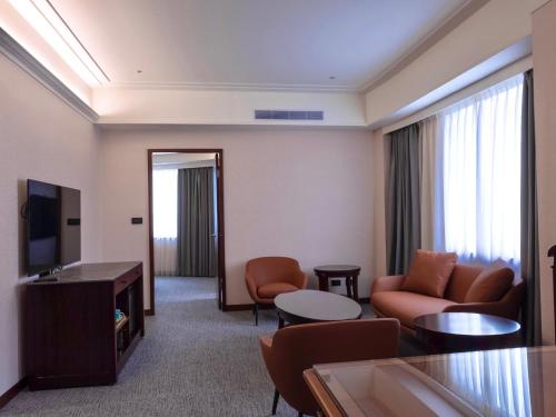a hotel room with a couch and a television at Fullon Poshtel Jhongli in Zhongli