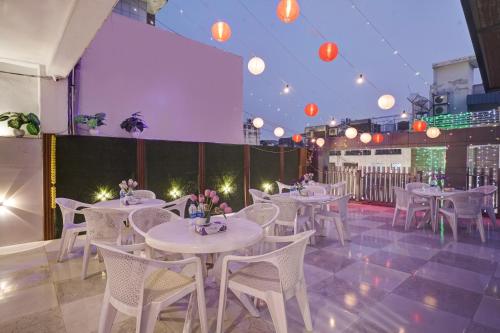 a restaurant with white tables and chairs and lights at Hotel Saina International - Near Connaught Place & New Delhi Railway Station in New Delhi