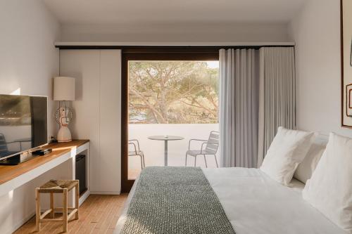 ein Schlafzimmer mit einem Bett, einem Fernseher und einem Tisch in der Unterkunft Boutique Hotel Villa Salvador - Adults Only by Fimedhotels in Cadaqués