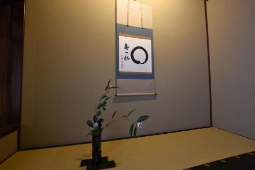 a vase on a table with a sign on a wall at 金沢之旅宿 あけぼの Kanazawa stay Akebono in Kanazawa