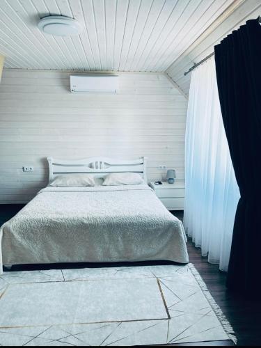a bedroom with a large bed with white sheets at Котедж Смерекова хата- Пилипець in Kelechin
