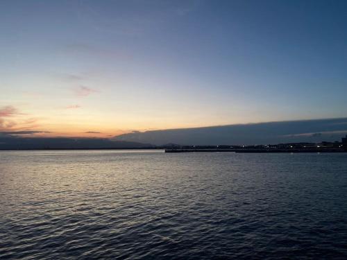 a large body of water with the sunset in the background at ESPLANADE VILLAGE HOTEL b in Kamakura