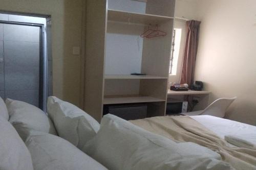 a bedroom with a white bed and a desk at Maluti Backpackers in Phuthaditjhaba
